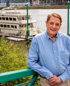 Wayne leaning on railing with Crystal Dolphin and Willamette River in background