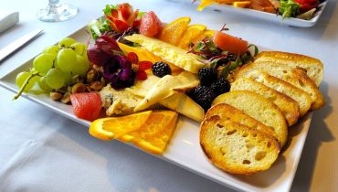 cheese platter plate with crostini, three types of local cheeses and fruit