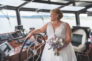 Bride with bouquet with hand on the wheel in the wheelhouse