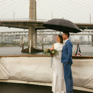 Wedding couple smiling on a boat despite the rain