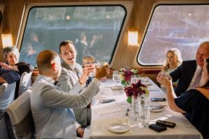 Cheersing on a boat on the Willamette River with flowers on the tables