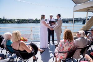 Couple gets married on boat by captain in front of a small number of guests.